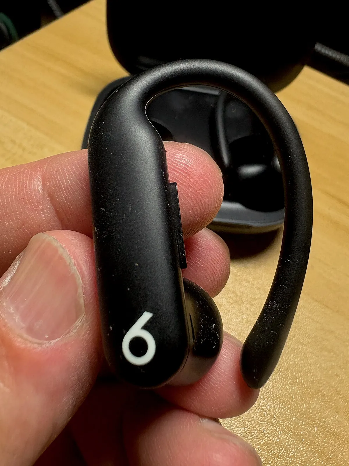 Wireless earbud held between two fingers