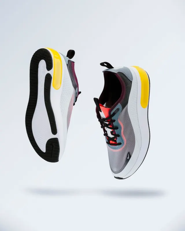 Two trainers floating on a light grey studio background, before background removal